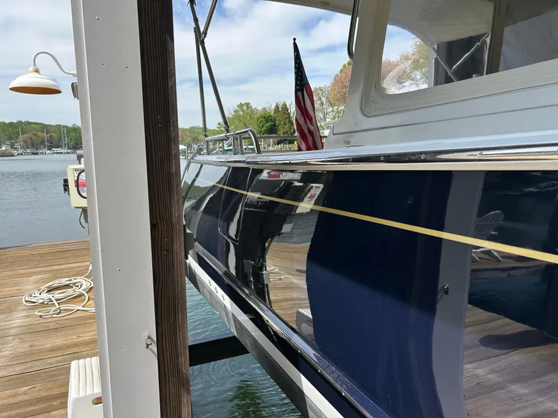 Slide: The Image of 2011 MJM 36Z yacht docked, featuring sleek blue hull and American flag. - 4