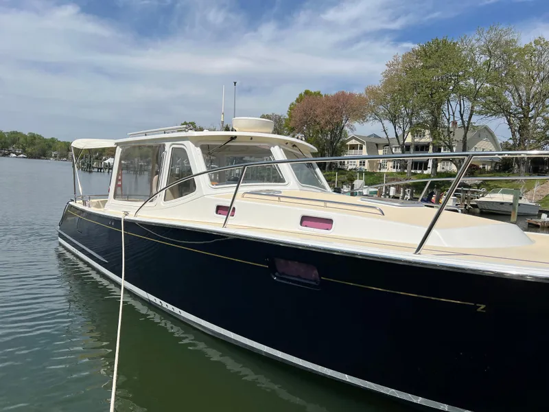 Slide: The Image of 2011 MJM 36Z boat docked on a calm lake with trees and houses in the background. - 9