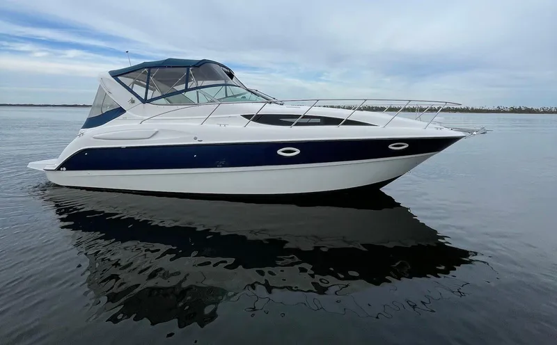 Slide: The Image of 2006 Bayliner 305 boat on calm water with blue and white design. - 0