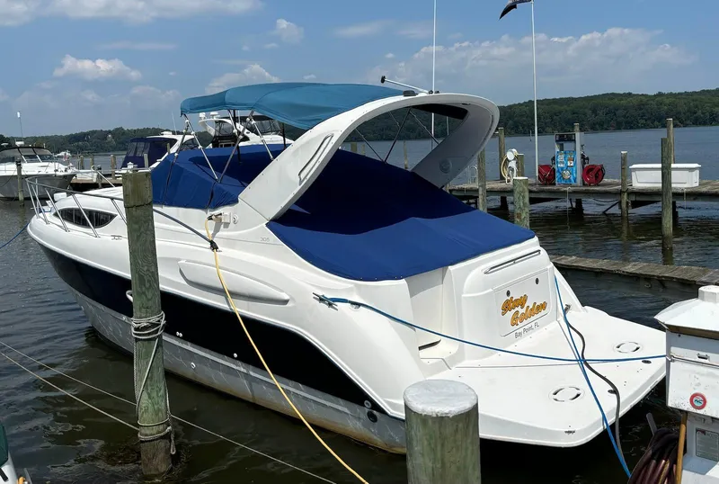 Slide: The Image of 2006 Bayliner 305 boat docked at a marina with blue canopy and cover. - 1