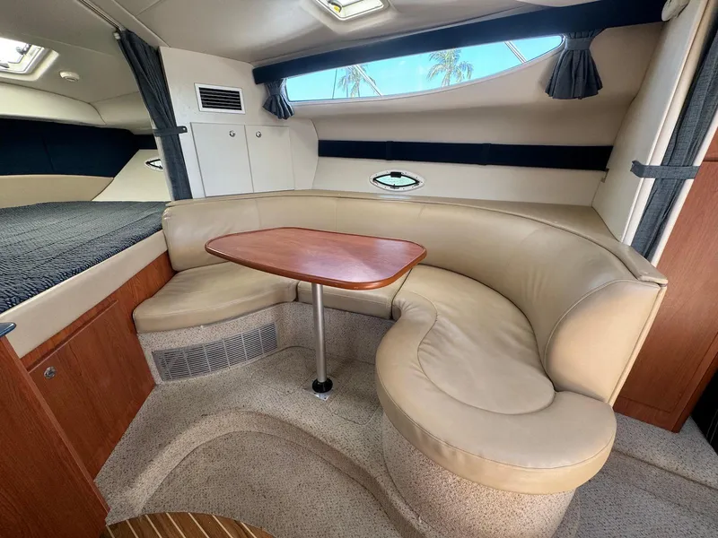 Slide: The Image of 2006 Bayliner 305 interior with beige seating and wooden table in cabin. - 13