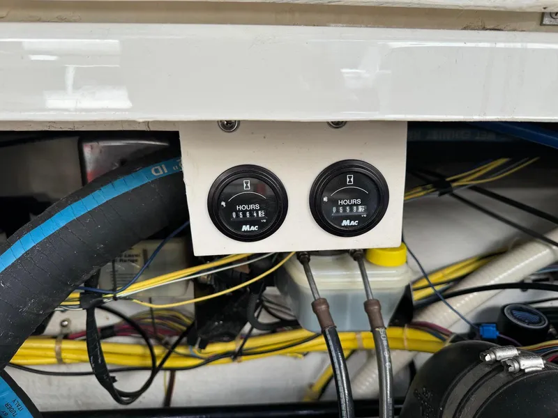 Slide: The Image of Engine hour meters on a 2006 Bayliner 305 boat, surrounded by wiring and hoses. - 18