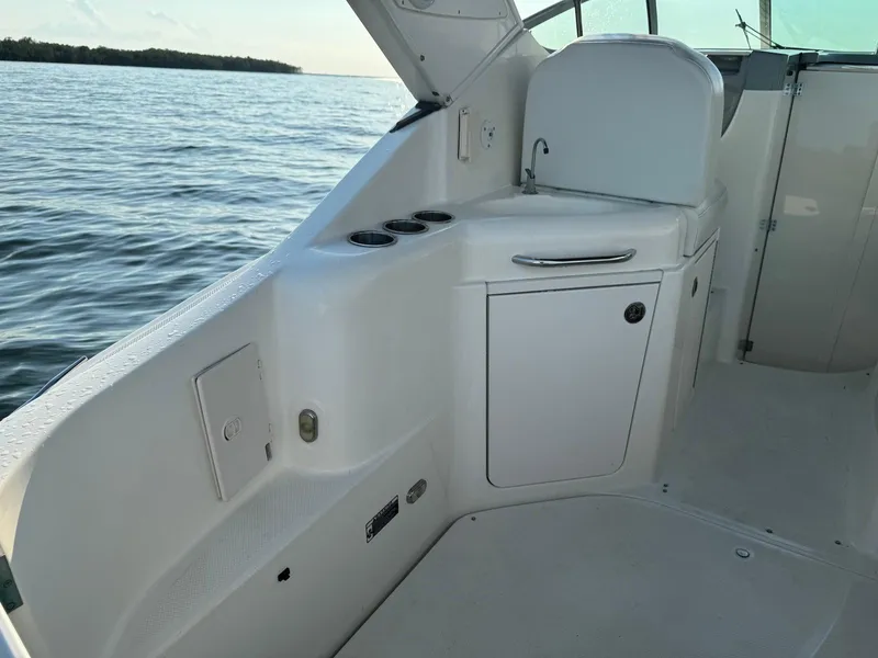 Slide: The Image of 2006 Bayliner 305 boat interior with storage and cup holders, on calm water. - 8
