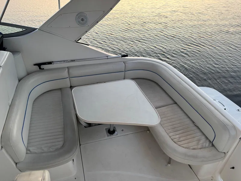 Slide: The Image of 2006 Bayliner 305 boat interior with white seating and table, overlooking calm water. - 9