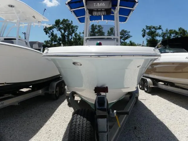 Slide: The Image of 2018 Robalo R180 boat on trailer, front view, with blue canopy, parked outdoors. - 2