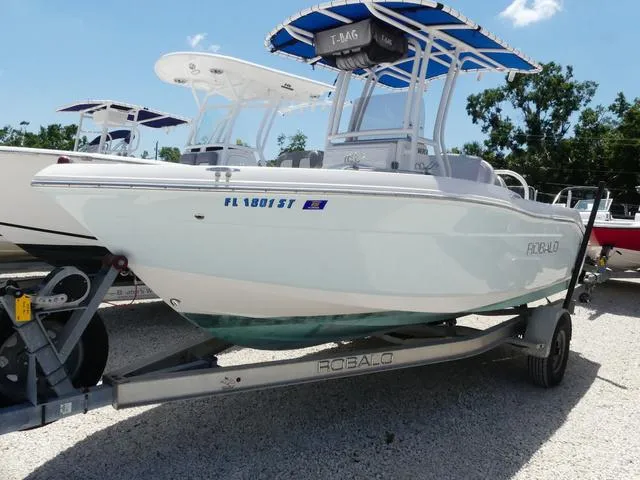 Slide: The Image of 2018 Robalo R180 boat on trailer with blue canopy, parked outdoors. - 3
