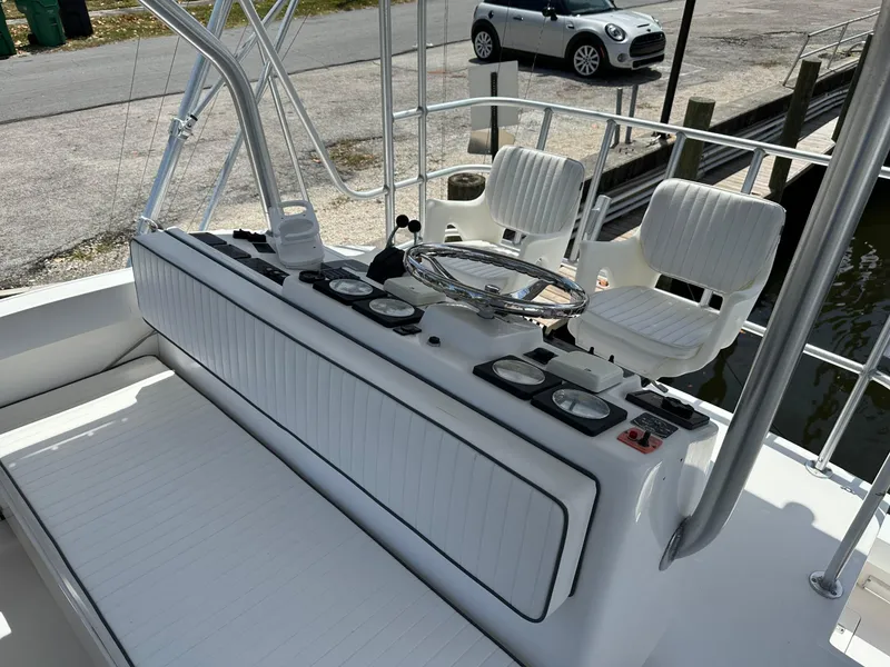 Slide: The Image of 2003 Luhrs 40 Convertible boat helm with white seating and steering wheel, docked near a Mini Cooper. - 19