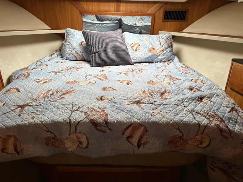 Slide: The Image of 2003 Luhrs 40 Convertible cabin with a cozy, nautical-themed bedspread and pillows. - 6