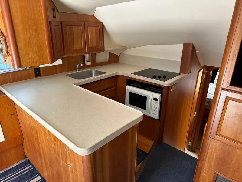 Slide: The Image of 2003 Luhrs 40 Convertible yacht kitchen with wood cabinetry, sink, stove, and microwave. - 9