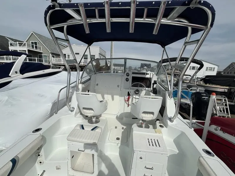 Slide: The Image of 2005 Polar 2300 boat interior with dual seats and control panel, docked near houses. - 12