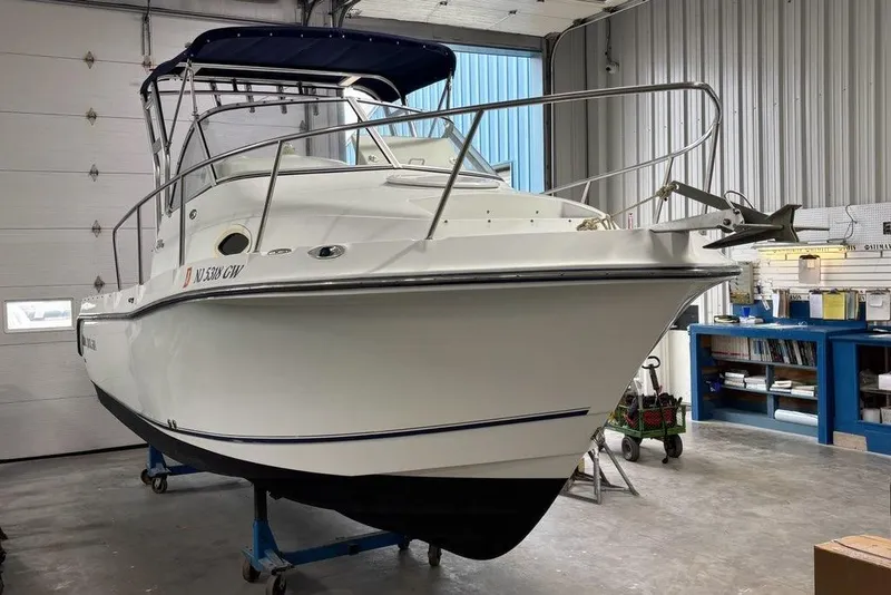 Slide: The Image of 2005 Polar 2300 boat in a garage, white hull, blue canopy, on a trailer. - 21