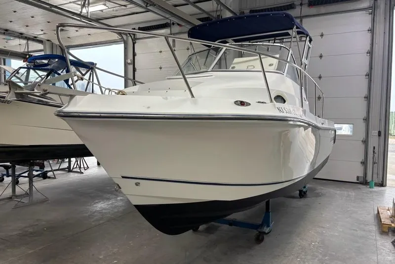 Slide: The Image of 2005 Polar 2300 boat in a garage, featuring a sleek white hull and blue canopy. - 22
