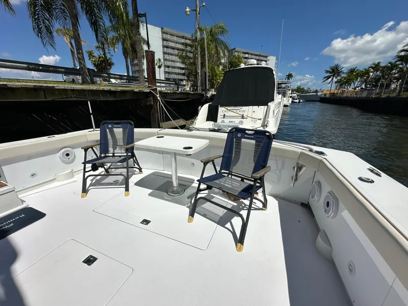 Slide: The Image of 1985 Bertram 46 Convertible yacht deck with chairs and table, docked by palm trees. - 11
