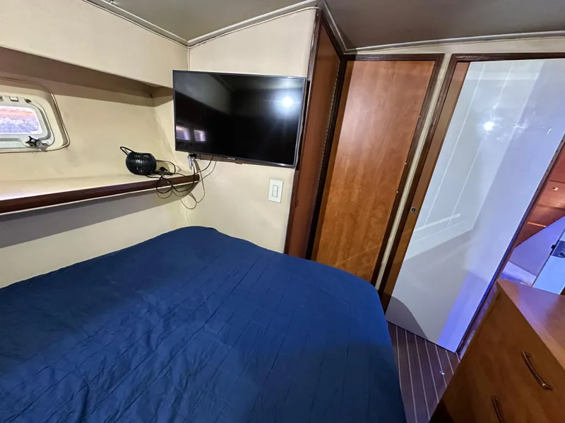 Slide: The Image of Cozy bedroom in 1985 Bertram 46 Convertible yacht with TV and blue bedding. - 24