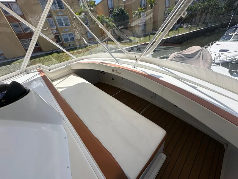 Slide: The Image of 1985 Bertram 46 Convertible boat interior with white seating and wooden deck. - 26