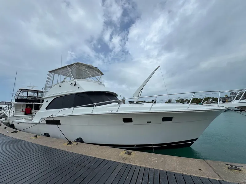Slide: The Image of 1985 Bertram 46 Convertible yacht docked at marina under cloudy sky. - 3