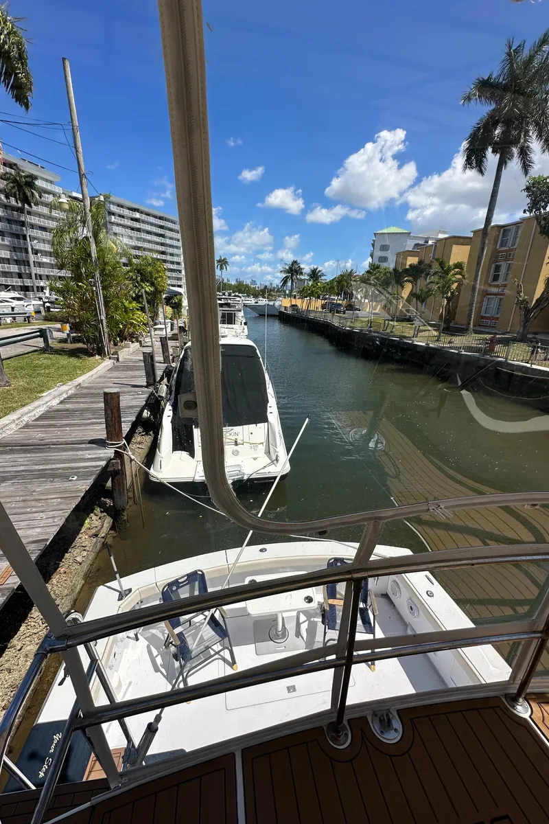 Slide: The Image of 1985 Bertram 46 Convertible docked in a sunny canal with palm trees and buildings nearby. - 43