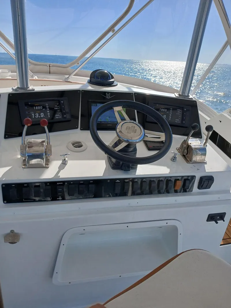 Slide: The Image of 1985 Bertram 46 Convertible yacht helm with ocean view, featuring steering wheel and control panels. - 9