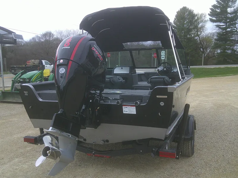 Slide: The Image of 2025 Lund 1875 Impact XS Sport boat with outboard motor, parked on a trailer. - 10