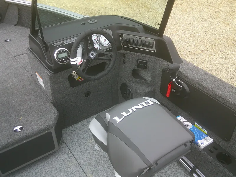 Slide: The Image of 2025 Lund 1875 Impact XS Sport boat interior with steering wheel and branded seat. - 17