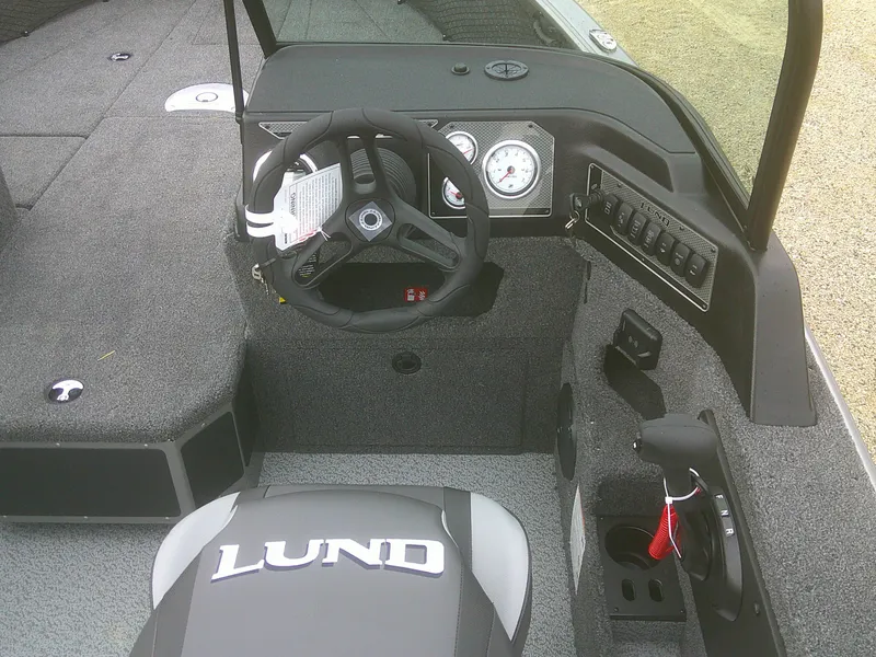 Slide: The Image of 2025 Lund 1875 Impact XS Sport boat interior with steering wheel and dashboard controls. - 18