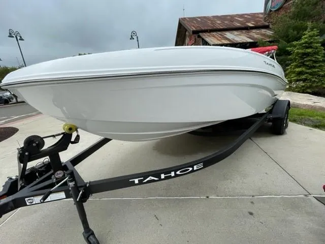 Slide: The Image of 2025 Tahoe T18 boat on trailer, parked outdoors, showcasing sleek white hull design. - 1