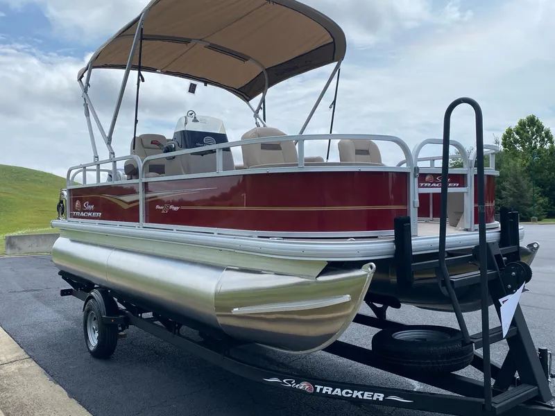 Slide: The Image of 2025 Sun Tracker Bass Buggy 18 DLX pontoon boat on trailer, red and silver design. - 5