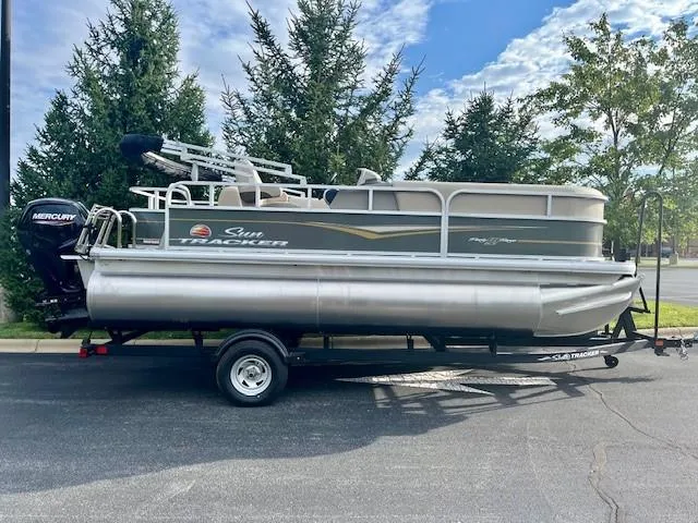 The Image of 2025 Sun Tracker Party Barge 18 DLX pontoon boat on trailer, parked outdoors. - 0