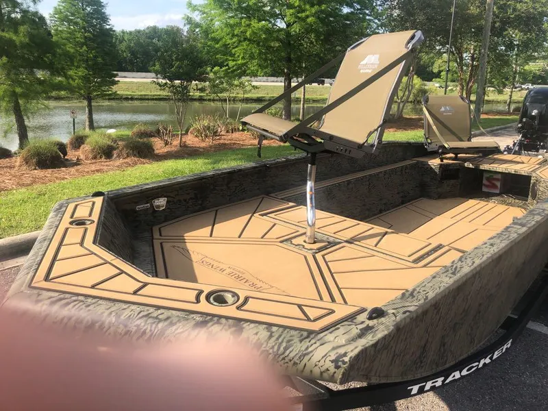 Slide: The Image of 2025 Tracker Grizzly 1650 T Prairie Wings Edition boat with camo design near a scenic lake. - 7