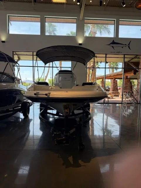 Slide: The Image of 2023 Tahoe 2150 CC boat displayed in a showroom with large windows. - 2