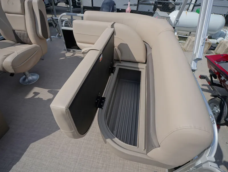 Slide: The Image of 2025 Sun Tracker Party Barge 16 DLX with open storage compartment on beige seating. - 9