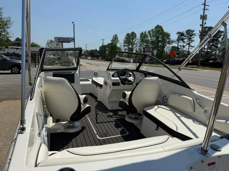 Slide: The Image of 2020 Stingray 191 DC boat interior with seating and steering wheel, parked outdoors. - 34