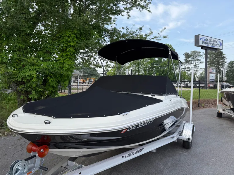 Slide: The Image of 2020 Stingray 191 DC boat on trailer with cover, parked outdoors near trees. - 36