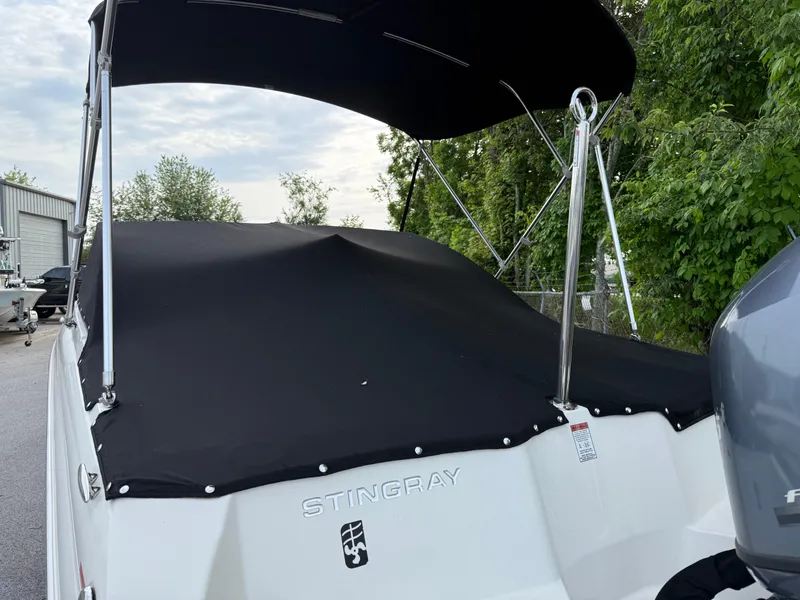 Slide: The Image of 2020 Stingray 191 DC boat with black cover and canopy, parked outdoors. - 39