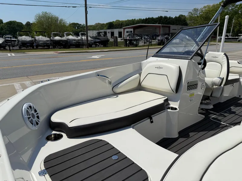 Slide: The Image of 2020 Stingray 191 DC boat interior with seating and dashboard, parked outdoors. - 9