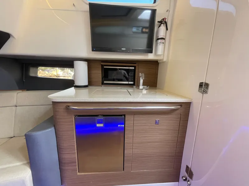Slide: The Image of Interior of 2017 Boston Whaler 420 Outrage featuring kitchenette with TV, microwave, and fridge. - 11