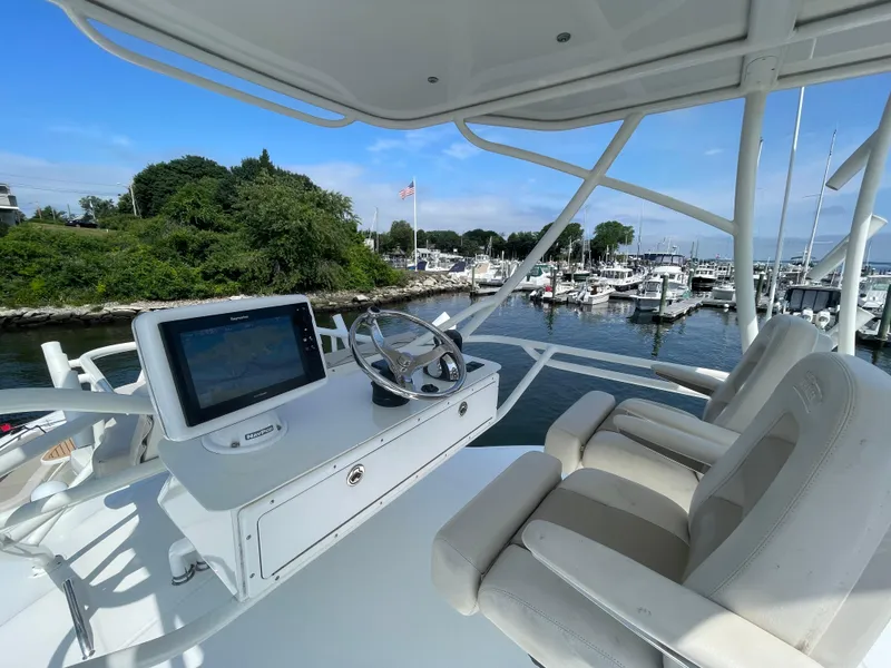 Slide: The Image of 2017 Boston Whaler 420 Outrage helm with dual seats, overlooking marina and lush greenery. - 19