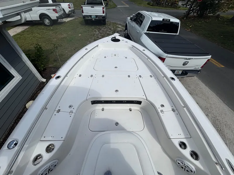 Slide: The Image of 2016 ShearWater 260 Carolina Bay boat, white deck, parked near trucks. - 18