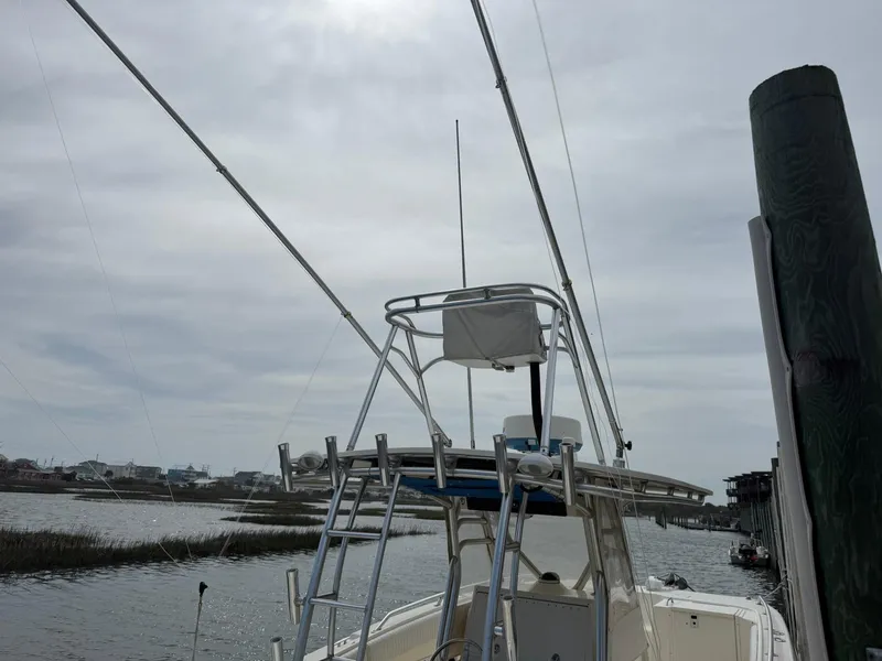 Slide: The Image of 2003 World Cat 330 TE boat docked, featuring fishing rods and a cloudy sky backdrop. - 9