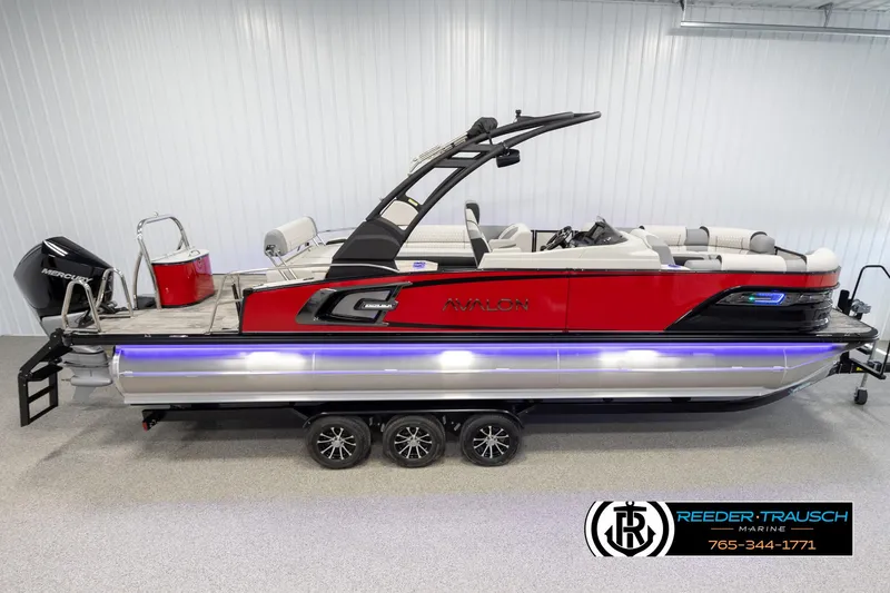 The Image of 2025 Avalon Excalibur LTD CRB pontoon boat, red and silver, in a showroom setting. - 1
