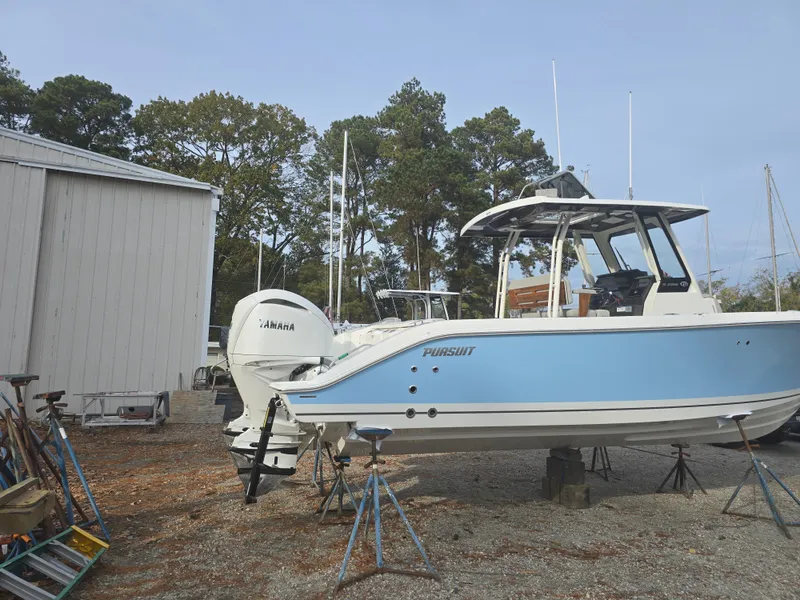 Slide: The Image of 2025 Pursuit S 288 boat on stands, outdoors near a storage building. - 3