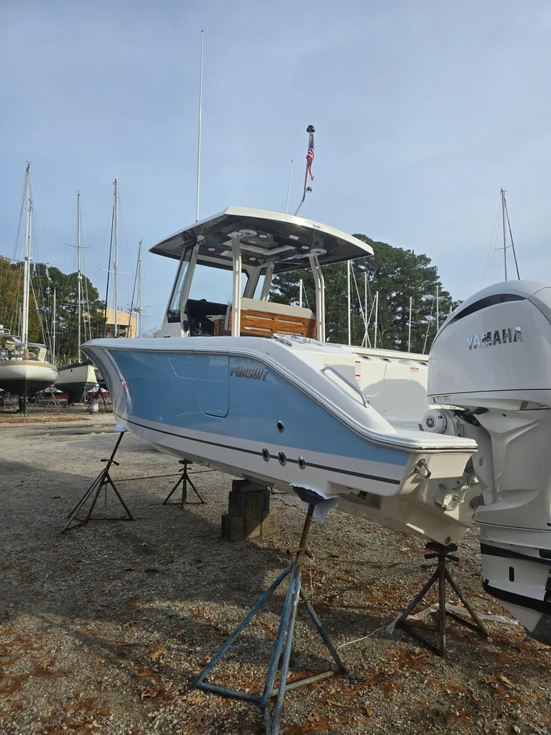 Slide: The Image of 2025 Pursuit S 288 boat on stands, blue and white hull, outdoor setting. - 5