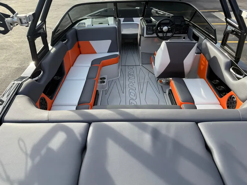 Slide: The Image of 2018 Moomba Helix boat interior with orange and gray seating, modern dashboard, and spacious layout. - 11