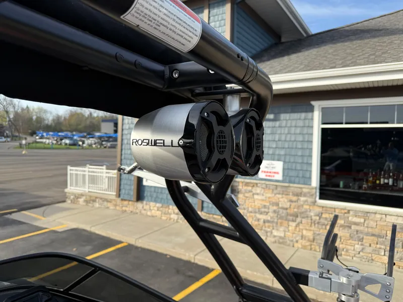 Slide: The Image of Roswell speakers mounted on a 2018 Moomba Helix boat, near a building and parking lot. - 12