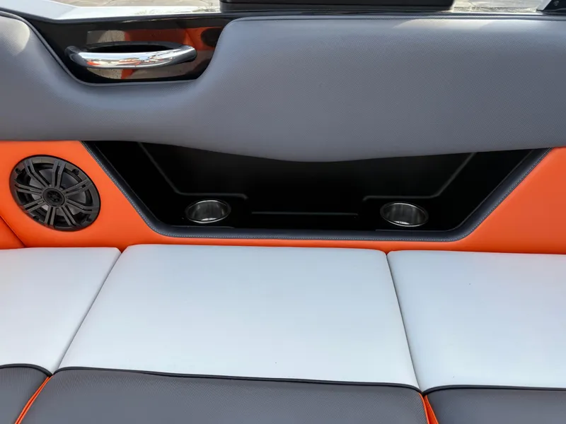 Slide: The Image of 2018 Moomba Helix boat interior with orange and gray seating, speaker, and cup holders. - 14