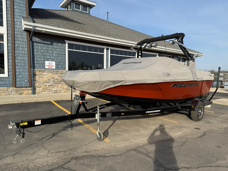 Slide: The Image of 2018 Moomba Helix boat on trailer, covered, parked outside a building. - 2
