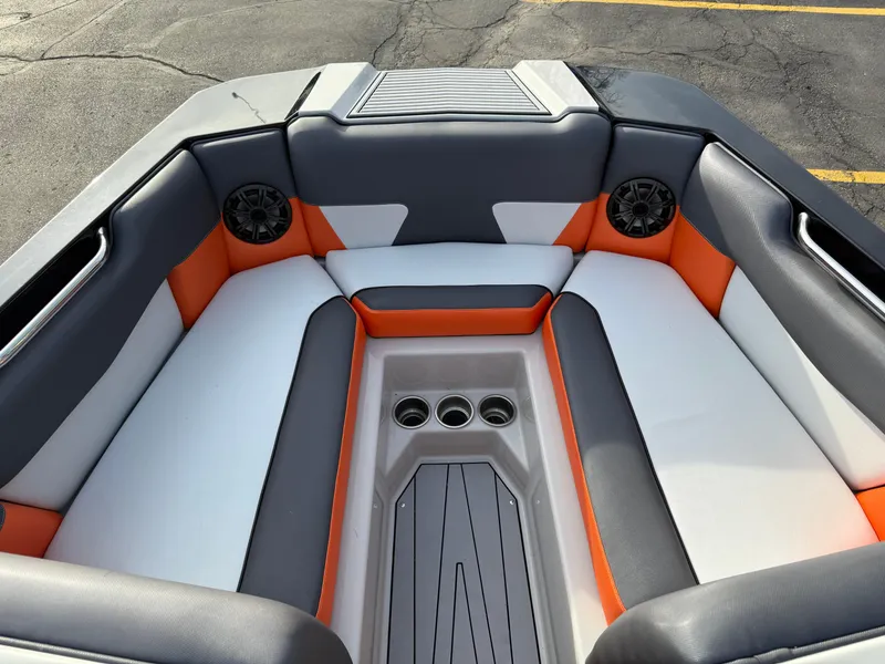 Slide: The Image of 2018 Moomba Helix boat interior with orange, gray, and white seating, featuring cup holders and speakers. - 21