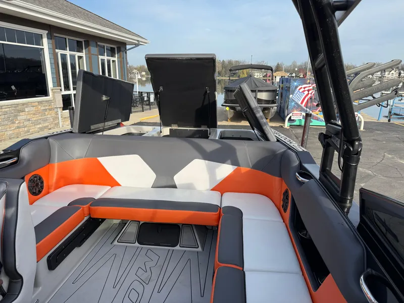 Slide: The Image of 2018 Moomba Helix boat interior with orange and gray seating, dockside view. - 22
