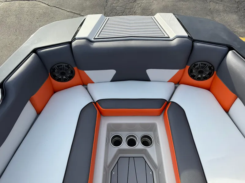 Slide: The Image of 2018 Moomba Helix boat interior with orange and gray seating, cup holders, and speakers. - 23