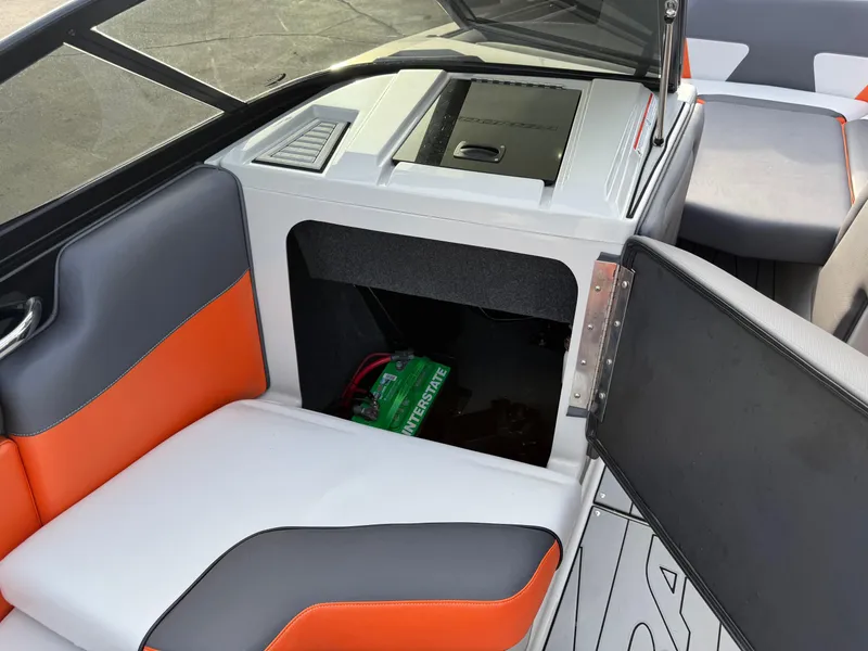 Slide: The Image of 2018 Moomba Helix boat interior with orange and gray seating, open storage compartment. - 28